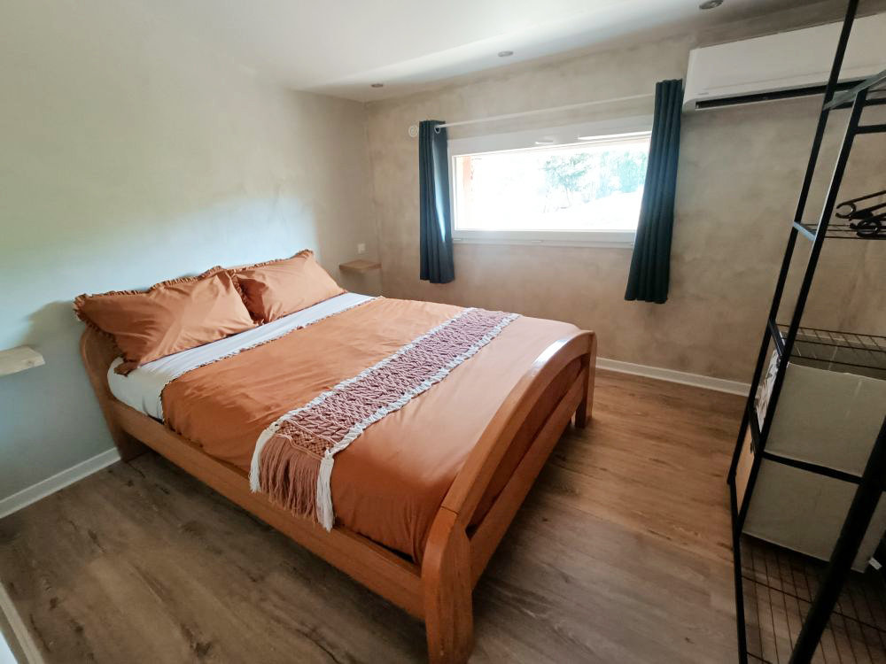 Première chambre climatisée de l'appartement le Romane à Vallon Pont d'Arc avec un lit deux places en 140, rangements et climatisation pour un séjour en Ardèche
