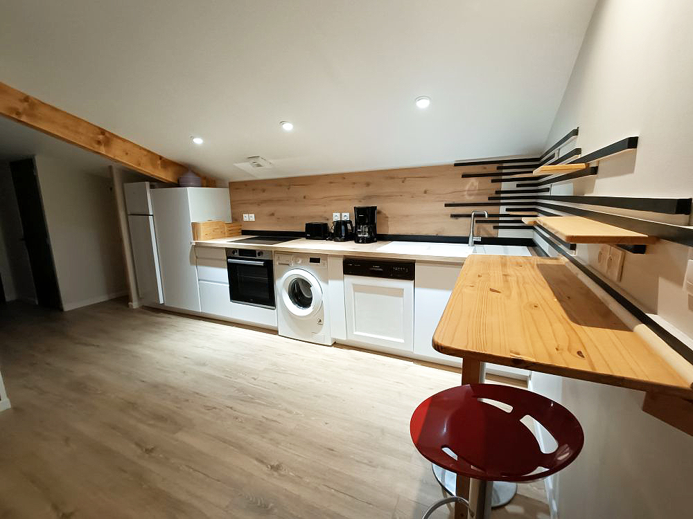 Cuisine entièrement équipée de l'appartement le Romane des gîtes de chrysmo à Vallon Pont d'Arc avec le lave-linge, lave vaisselle, four, micro onde et espace repas en Ardèche