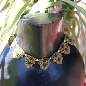 Collier en micro-macramé vert olive avec pierres de lave fait main par les Créas de Chrys, présenté sur un buste en bois décor végétal
