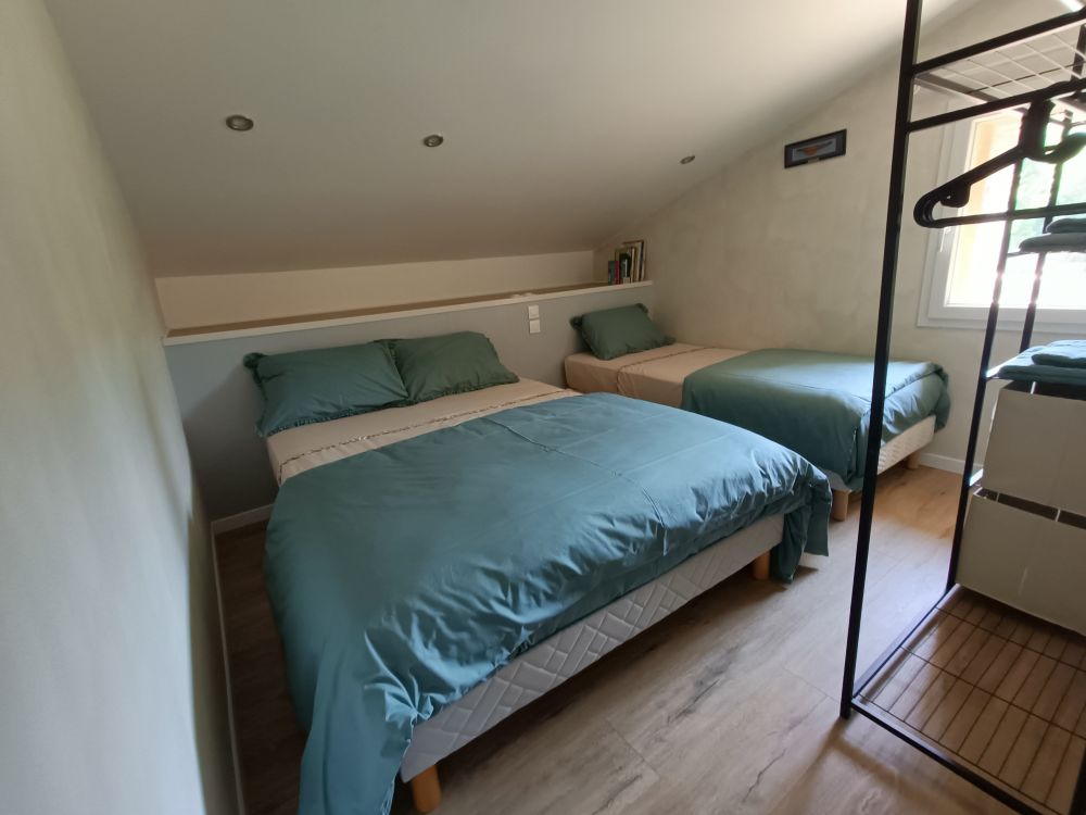 Chambre mansardée de l'appartement le Romane chez les gîtes de chrysmo à Vallon Pont d'Arc, avec un lit double en 140 et un lit simple en 90 et une penderie, pour un séjour en Ardèche